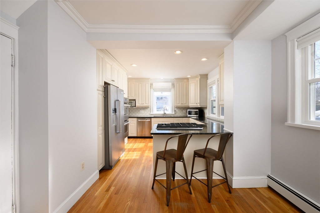 1099 Brook Road Milton, MA 02186 - Photo 11 of 41 a kitchen with stainless steel appliances granite countertop a stove top oven a sink and white cabinets with wooden floor