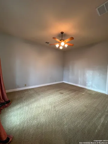 a view of an empty room with a chandelier fan