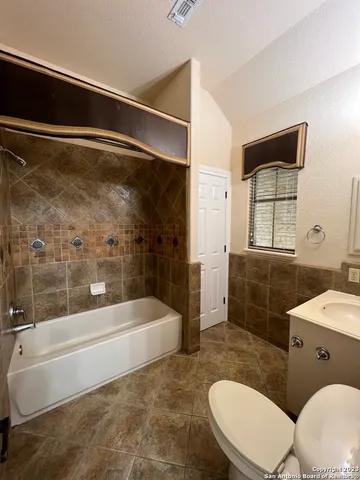 an empty room with a chandelier fan and windows