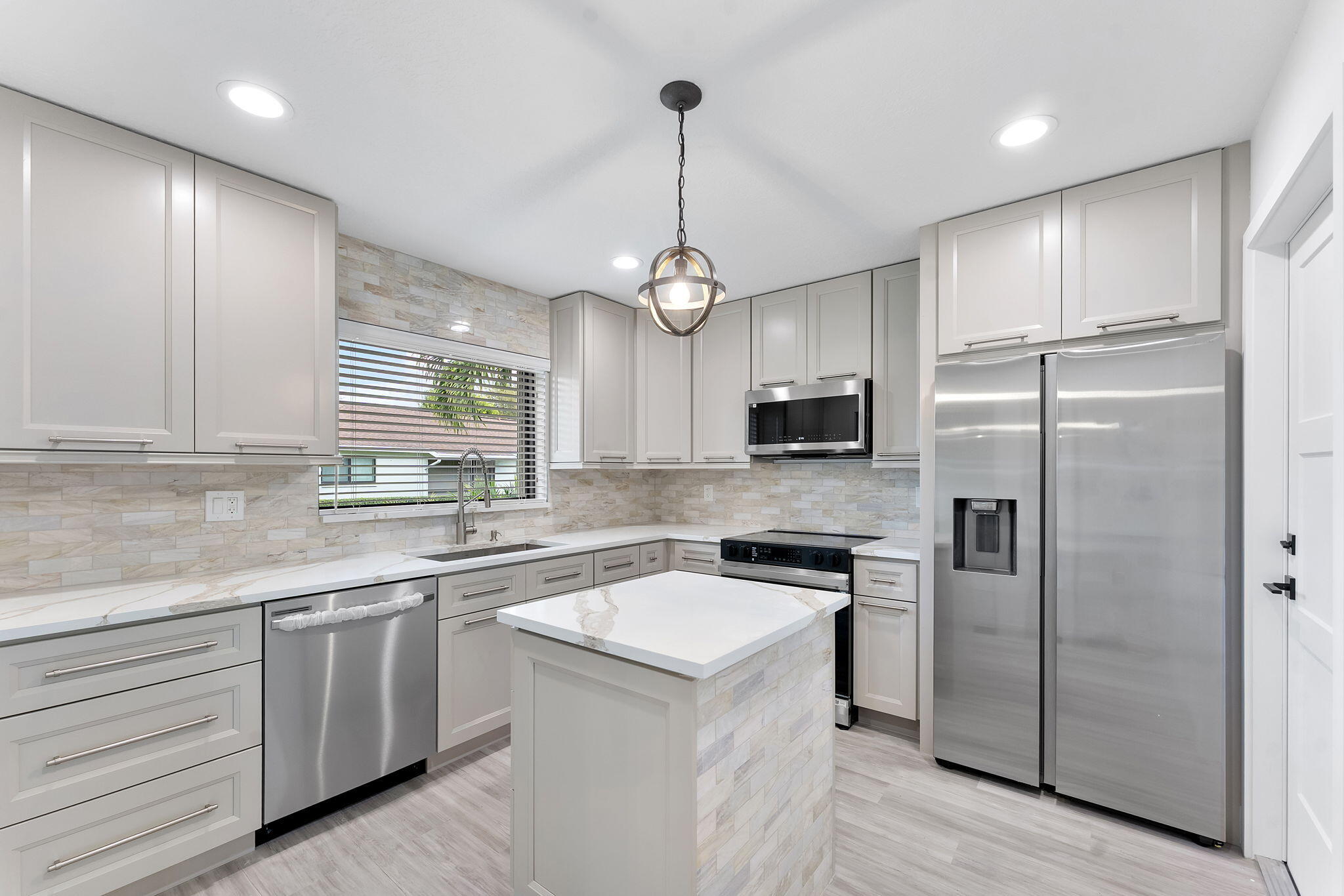 a kitchen with a sink a center island cabinets and stainless steel appliances