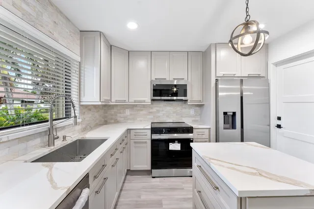 a kitchen with stainless steel appliances granite countertop a sink a stove a refrigerator cabinets and a counter top space