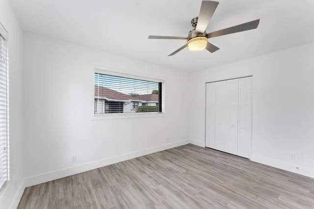 a view of empty room with wooden floor and fan