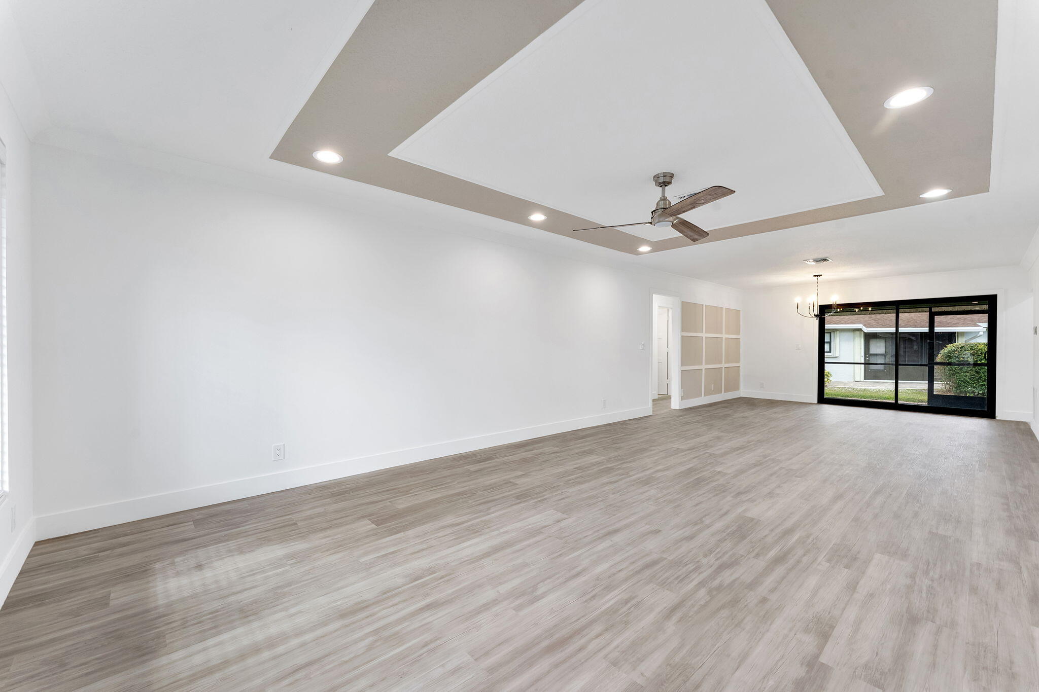 9840 Chestnut Tree Terrace, Unit A Boynton Beach, FL 33436 - Photo 4 of 27 an empty room with wooden floor ceiling fan and windows