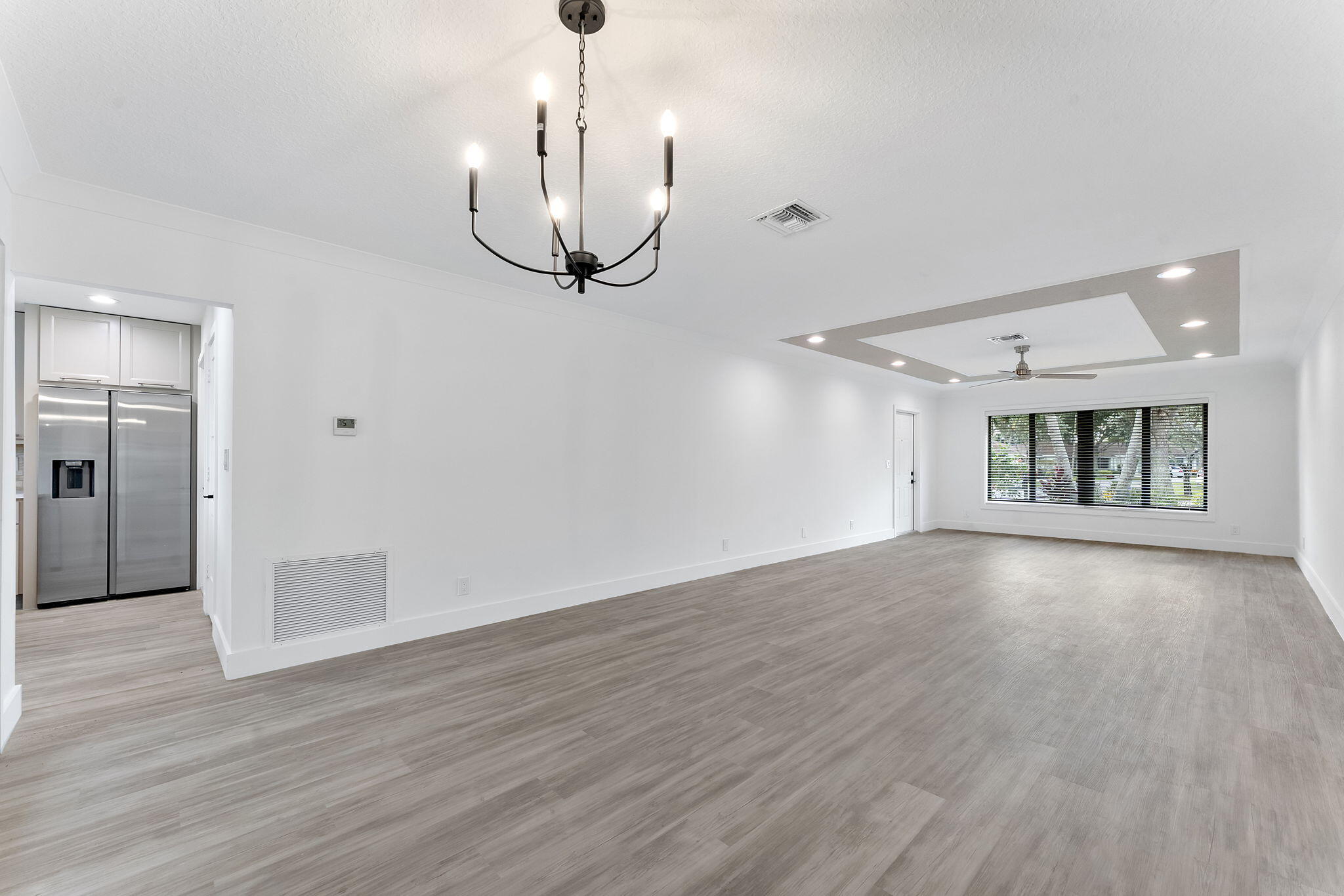 9840 Chestnut Tree Terrace, Unit A Boynton Beach, FL 33436 - Photo 7 of 27 a view of an empty room with wooden floor and a chandelier