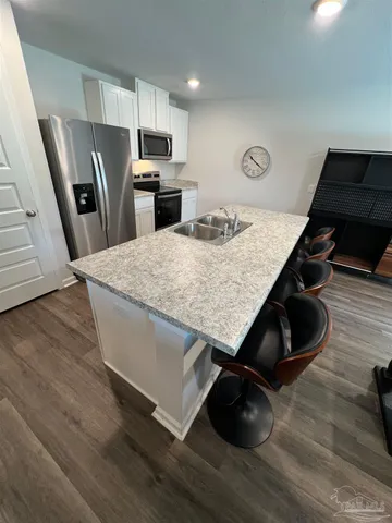a living room with stainless steel appliances furniture and a wooden floor