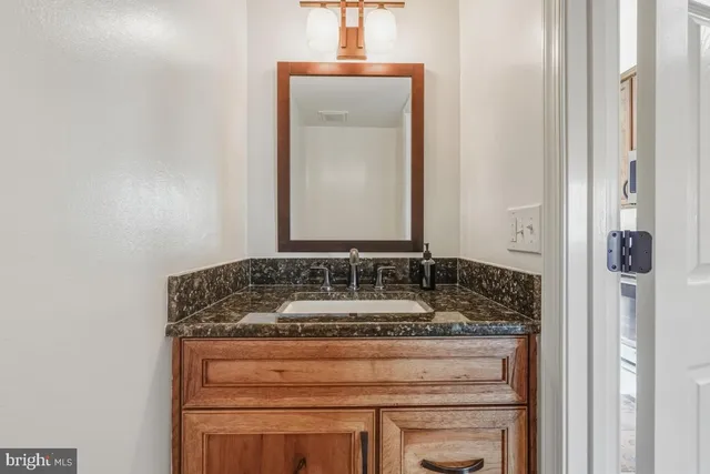 a bathroom with a granite countertop sink and a mirror