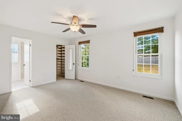 an empty room with windows and fan