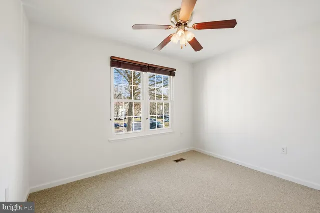 a view of an empty room with stairs and a ceiling fan