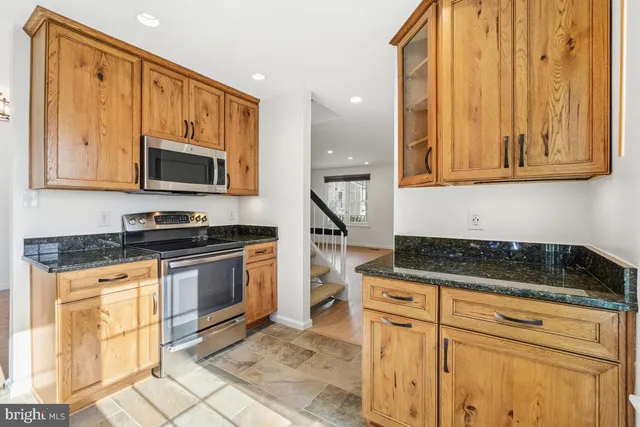 a kitchen with granite countertop a stove a sink and a microwave