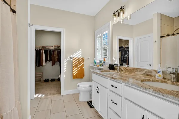 a spacious bathroom with a granite countertop sink a toilet and mirror