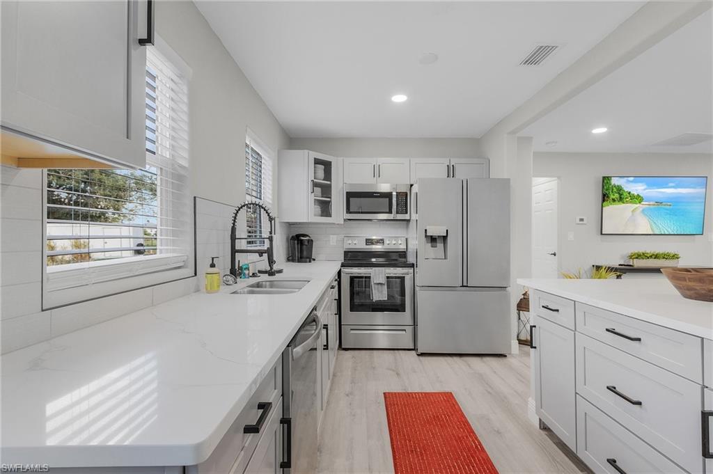 16075 Quail Trail Bokeelia, FL 33922 - Photo 8 of 24 a kitchen with stainless steel appliances granite countertop a refrigerator sink and stove