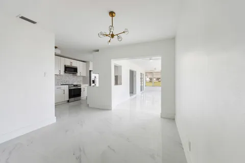 a view of a kitchen with a sink and dishwasher a refrigerator with white cabinets