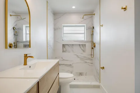 a bathroom with a sink a toilet and shower