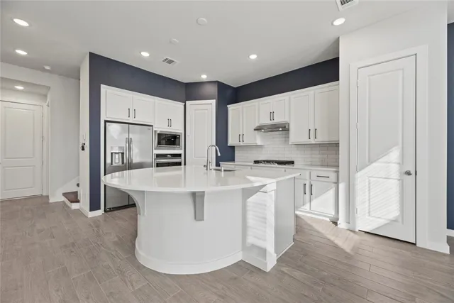 a kitchen with stainless steel appliances granite countertop a refrigerator sink and white cabinets