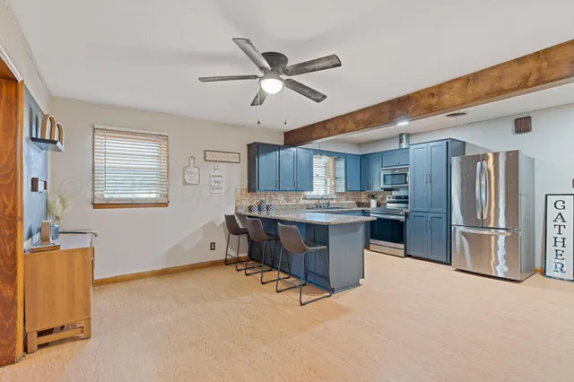a kitchen with stainless steel appliances kitchen island granite countertop a refrigerator a stove a sink dishwasher and a dining table with wooden floor