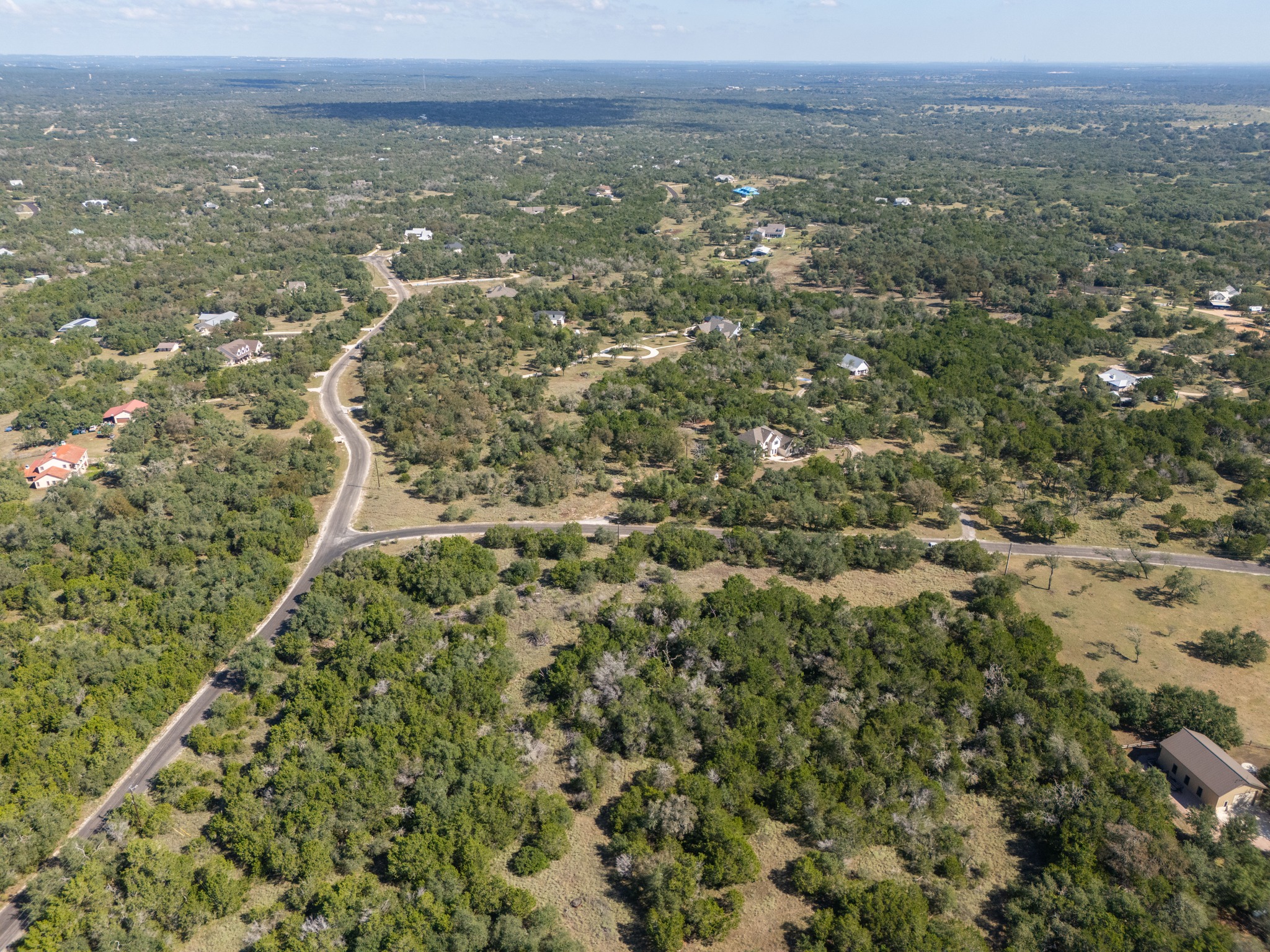 1001 Bluff View Road Wimberley, TX 78676 - Photo 6 of 20 Mature trees blanket the rolling hills of this expansive neighborhood landscape.