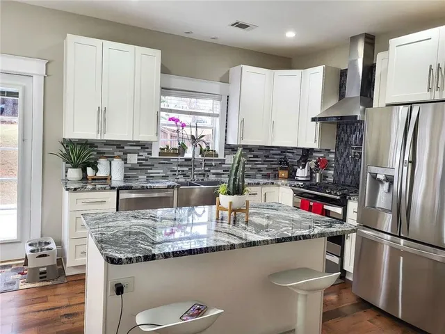 a kitchen with stainless steel appliances granite countertop a sink a stove and a refrigerator