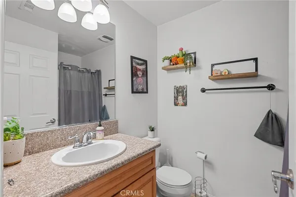 a bathroom with a granite countertop sink a toilet and a mirror