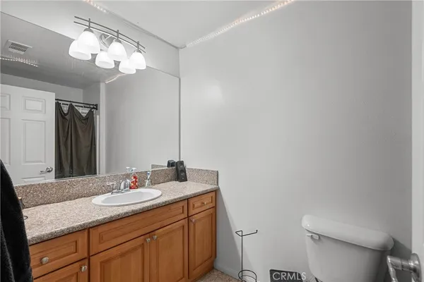 a bathroom with a granite countertop sink a toilet and a mirror