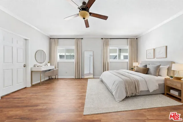 a spacious bedroom with a bed a dresser and a chandelier