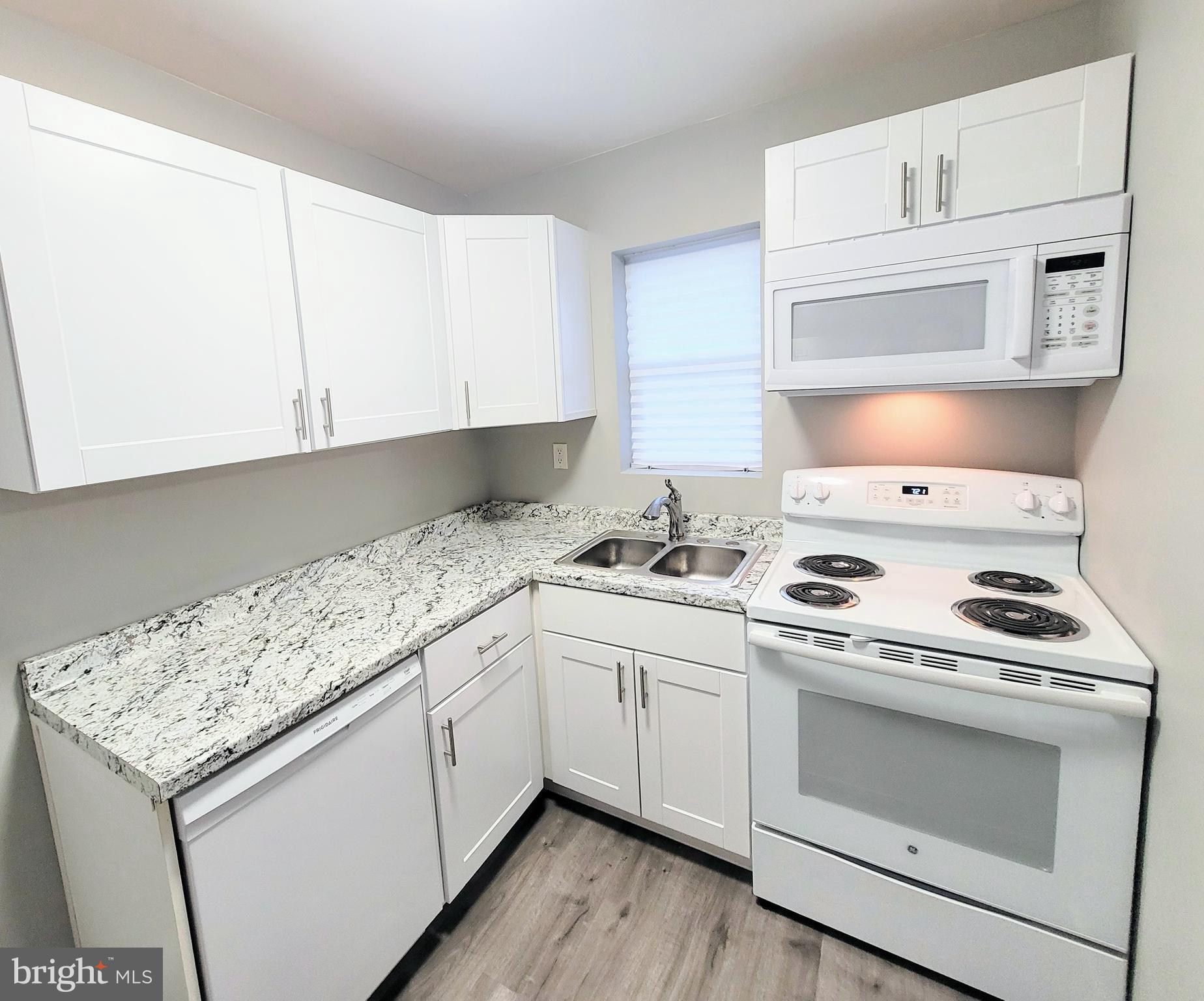 a kitchen with granite countertop white cabinets and white stove