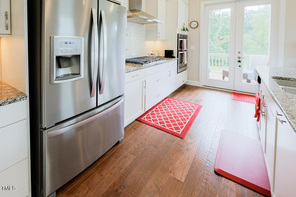 910 Wake Towne Drive Raleigh, NC 27609 - Photo 8 of 45 a kitchen with stainless steel appliances granite countertop a refrigerator a stove and white cabinets with wooden floor
