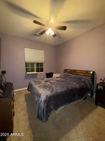 a bed sitting in a spacious bedroom and night stand
