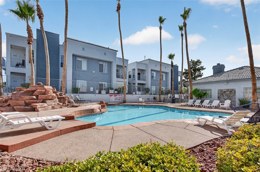 2201 Ramsgate Drive, Unit 1011 Henderson, NV 89074 - Photo 40 of 40 A tranquil community pool area, surrounded by swaying palms and contemporary residential buildings, invites relaxation.