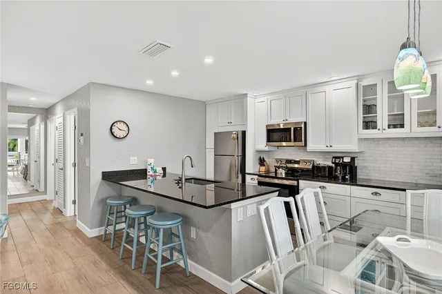 a kitchen with stainless steel appliances granite countertop a refrigerator a stove a sink a dining table and chairs with wooden floor