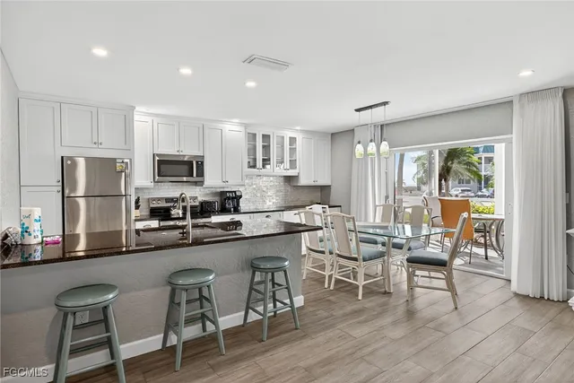 a kitchen with stainless steel appliances a dining table chairs refrigerator and microwave