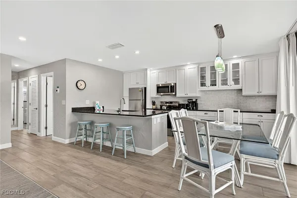 a kitchen with stainless steel appliances granite countertop a stove top oven a refrigerator a dining table and chairs with wooden floor