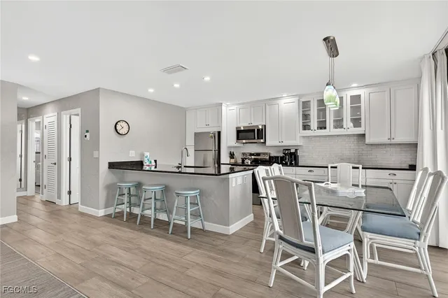 a kitchen with stainless steel appliances granite countertop a stove top oven a refrigerator a dining table and chairs with wooden floor