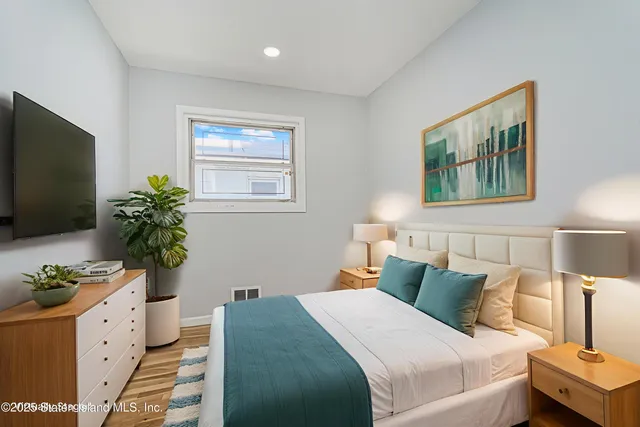 a bedroom with a bed potted plant on the dresser and a potted plant