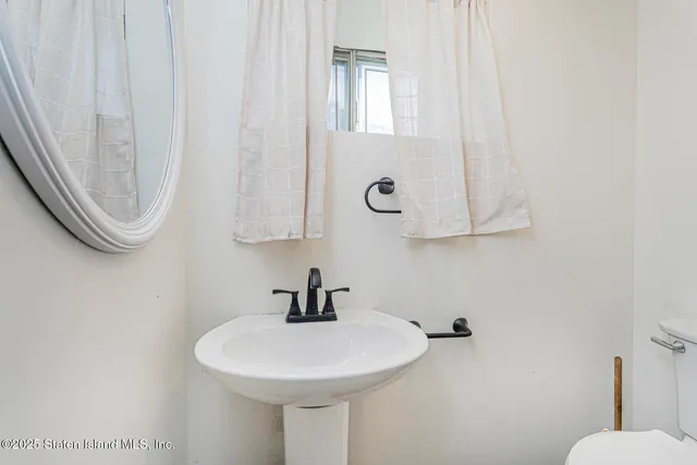 a view of a hallway with wooden floor and a bathroom