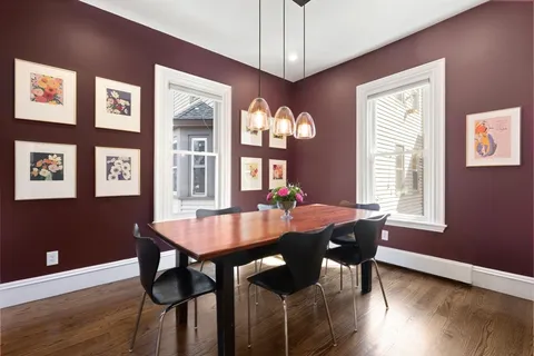 a dining room with wooden floor a chandelier a wooden table and chairs