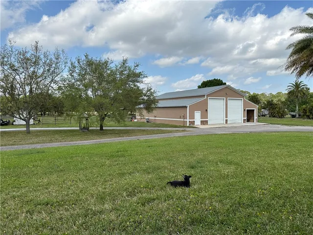 a view of a house with a big yard and large trees