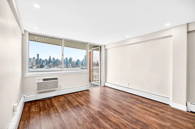 a view of an empty room with wooden floor and stairs
