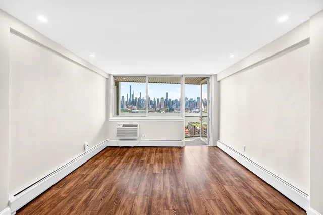 a view of empty room with wooden floor and window