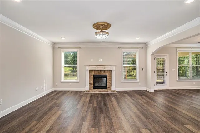 a view of an empty room with wooden floor fireplace and a window