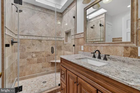 a bathroom with a granite countertop sink a mirror and shower