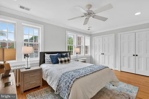 a spacious bedroom with a large bed a chandelier and windows