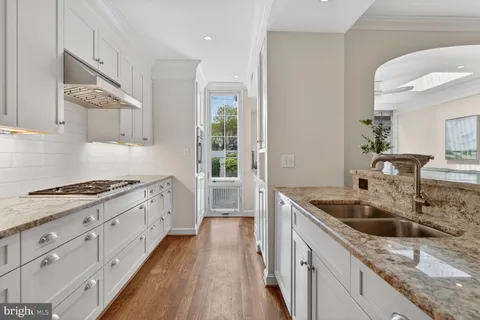 a kitchen with granite countertop a sink stove and cabinets