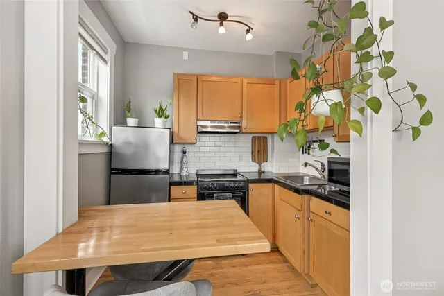 a kitchen with kitchen island a counter top space a sink a refrigerator and a window