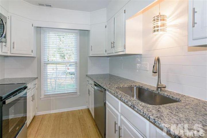 3148 Morningside Drive Raleigh, NC 27607 - Photo 8 of 24 a kitchen with granite countertop a sink dishwasher and cabinets next to a window