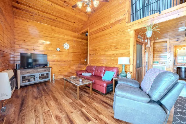 a living room with furniture a flat screen tv and floor to ceiling window