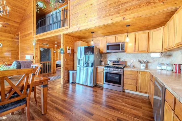 a kitchen with stainless steel appliances a stove a sink dishwasher a refrigerator and cabinets with wooden floor