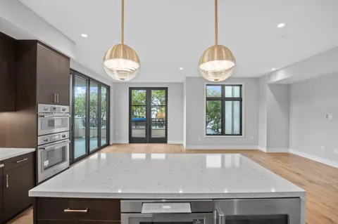 a view of a kitchen with granite countertop a stove a kitchen island a window and a counter top space