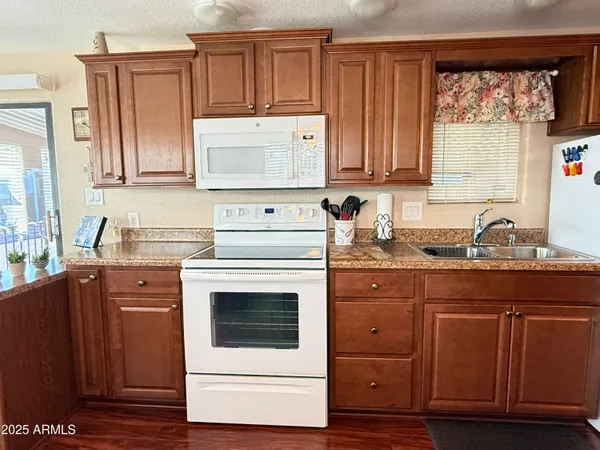 a kitchen with granite countertop wood cabinets stainless steel appliances and a sink