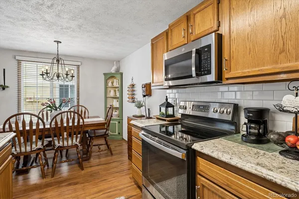a kitchen with granite countertop a stove a sink a dining table and chairs
