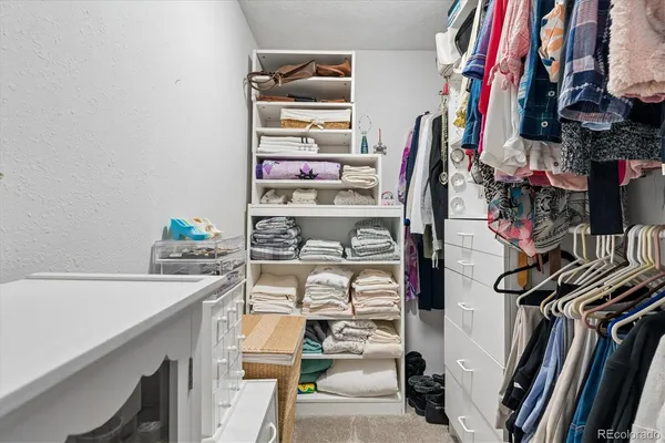 a view of walk in closet with clothes and shoes